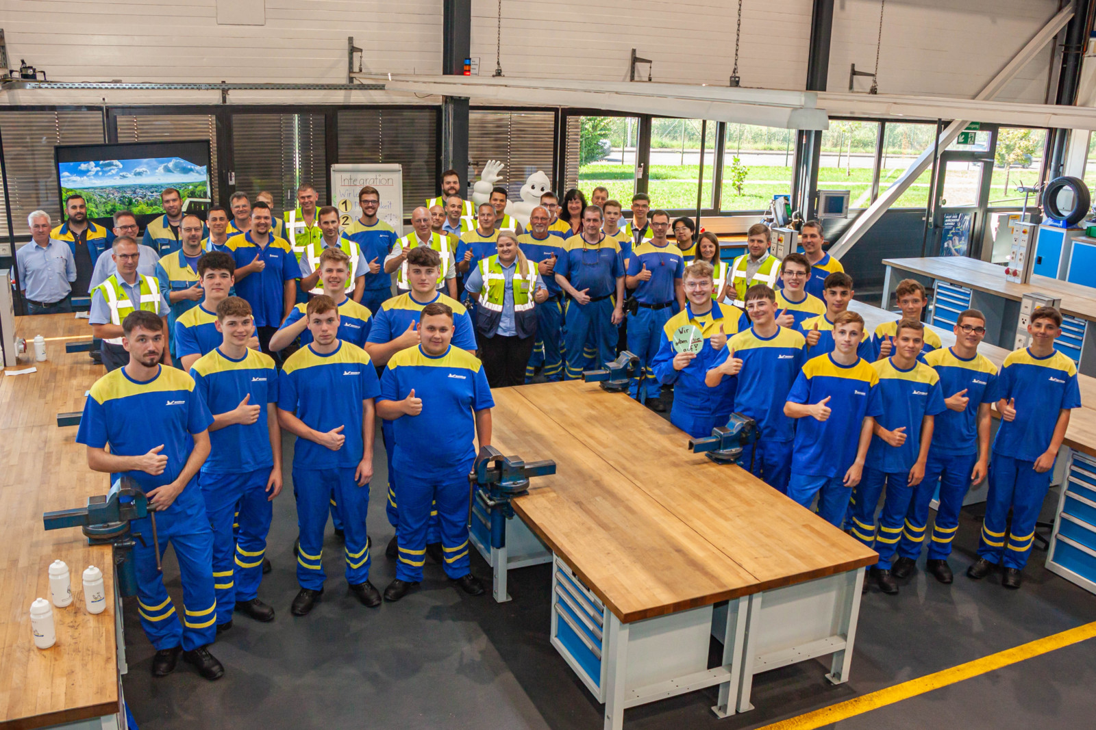 Kennenlernen in der Ausbildungswerkstatt: Die 16 neuen Michelin-Azubis (im Vordergrund) mit Werkdirektor Cyrille Beau, ihren Ausbildern, Fachkollegen und Direktionsteam-Mitgliedern.